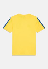 Rumena bombažna majica s krojenim ovratnikom, ki ima modre črte po ramenih. Kratke rokave in klasičen kroj.