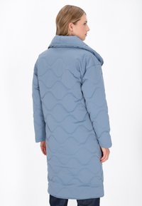 Cappotto lungo trapuntato di colore azzurro chiaro con un motivo ondulato, ampio colletto e tasche laterali, realizzato in materiale sintetico. Vista posteriore mostrata.