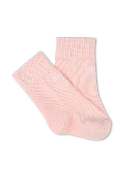 Chaussettes en coton rose avec des bords côtelés et une texture lisse, présentant un lettrage blanc subtil sur le côté. Design court jusqu'à la cheville.