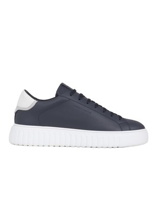 Sneaker blu navy a taglio basso con linguetta del tallone bianca, lacci neri e suola spessa bianca scanalata, vista laterale.