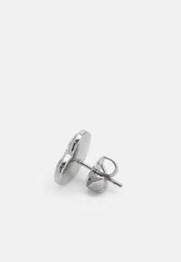 Silver stud earrings featuring a round backing and a detailed clasp. The surface is smooth with a reflective finish.