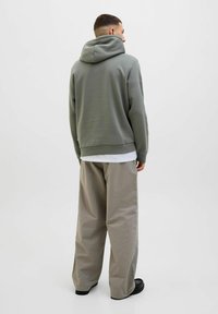 Gray hooded sweatshirt with a relaxed fit, paired with light beige, oversized pants. Simple design with no visible embellishments.