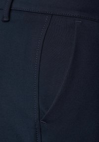 Pantaloni blu navy con una texture liscia, dotati di una tasca frontale e cuciture a contrasto lungo le cuciture. Progettati per un look casual.