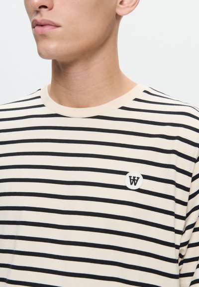 T-shirt w paski w beżowym i czarnym kolorze, z okrągłym dekoltem i haftowanym logo "W" na okrągłej naszywce. Miękka, lekka tkanina.