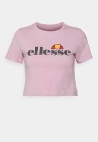 Svetle růžové zkrácené tričko vyrobené z bavlny s kulatým výstřihem, s černým logem "ellesse" a nad ním grafickou ilustrací slunce v červené a žluté barvě.