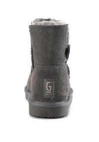 Botín de ante gris con un suave forro interior, parte superior curvada, punta redonda y un adorno de botón negro. Cuenta con una suela de goma texturizada.