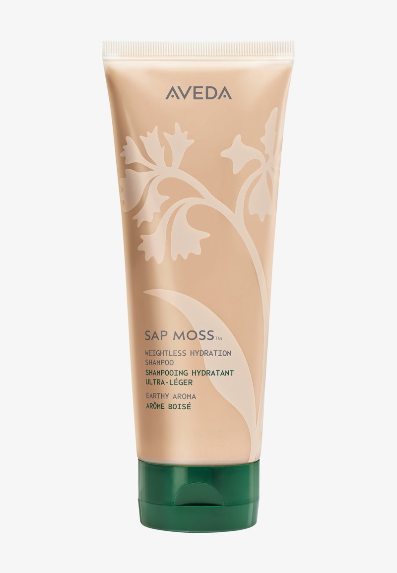 Tube de shampooing Aveda Sap Moss Weightless Hydration avec un design floral, un emballage beige, un capuchon vert et un texte décrivant un arôme terreux et une hydratation.