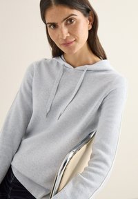 Felpa con cappuccio grigio chiaro realizzata in tessuto morbido, con cappuccio regolabile con coulisse, polsini a costine e vestibilità comoda. Dettagli in metallo color argento.