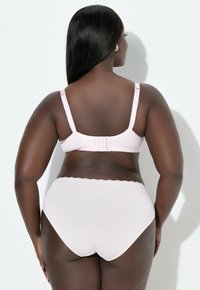 Vaaleanpunainen rintaliivisetti, johon kuuluu säädettävillä olkaimilla varustetut rintaliivit ja niihin sopivat alushousut. Setissä on pitsireunus, sileä kangas ja saumaton muotoilu, esitetty takaa.