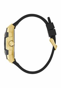 Montre noire avec accents dorés, un cadran rectangulaire, un bracelet en caoutchouc, des détails en relief, et une couronne latérale pour les réglages.