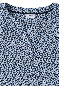 Blå og hvid bluse med bladmønster, delt halsudskæring og en påsyet "CECIL"-label ved kraven.