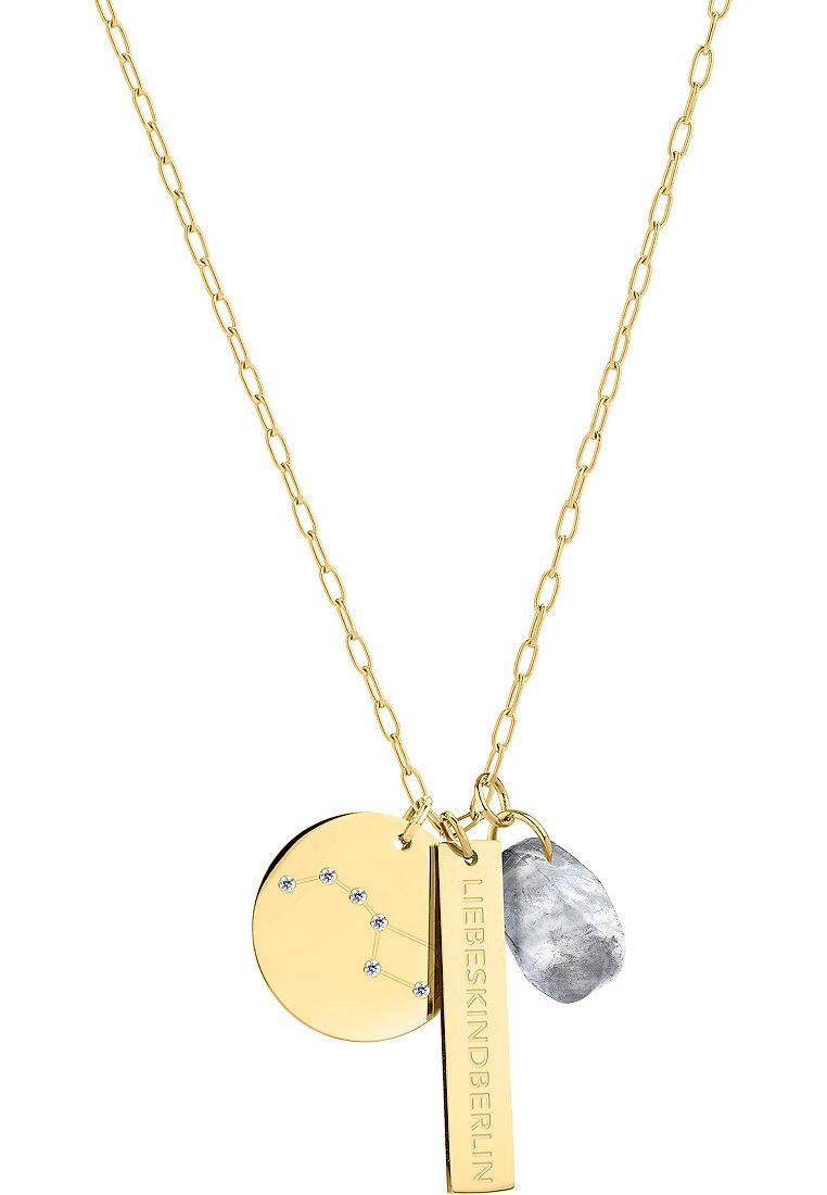 Collier en ton or avec une chaîne, comportant trois pendentifs : un disque rond au design de constellation, une étiquette rectangulaire gravée "LIEBESKIND" et une pierre grise texturée.