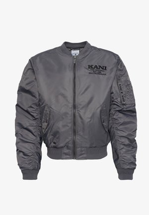 Veste bomber gris charbon avec fermeture éclair frontale, deux poches latérales, poignets côtelés et poche zippée sur la manche gauche, avec texte du logo "KANI".