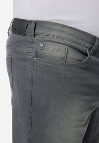 Grå denimjeans med smal passform. Har en läderetikett på midjebandet, fem fickor och metallhardware-accenter.