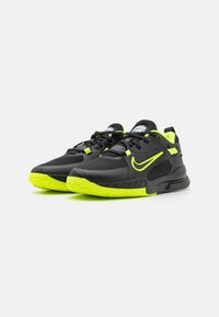 Crne atletske tenisice s neonsko zelenim akcentima, gornjište od mrežaste tkanine, podstavljeni ovratnik i teksturirana potplata za bolje prianjanje. Ističe se istaknuti Nike logotip.