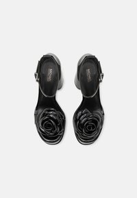 Escarpins en cuir noir à bout ouvert avec une bride de cheville, dotés d'une accent en rose noir brillant au niveau des orteils et d'un solide talon bloc.