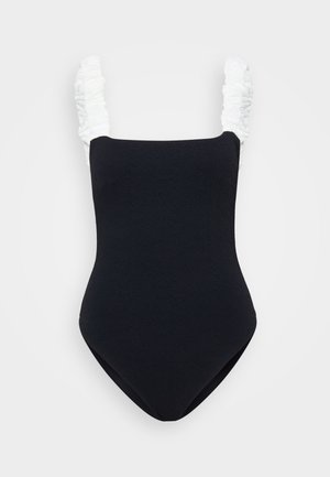 Bañador de una pieza negro con tejido texturizado, que presenta tirantes azulados con volantes. Escote rectangular y diseño de pierna alta.