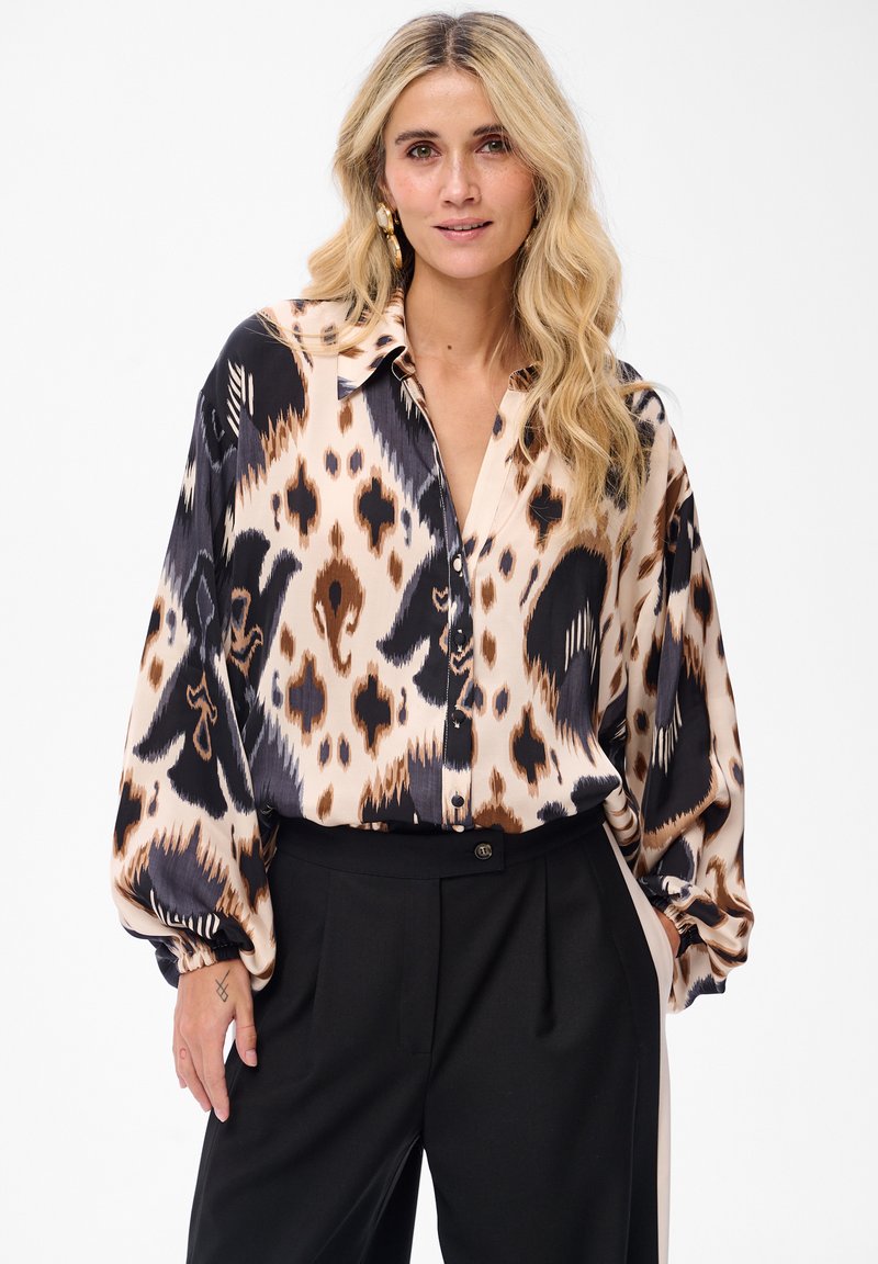 Long-sleeve blouse in a multicolored animal print, featuring shades of beige, black, and brown. Soft fabric, relaxed fit, and buttoned front.