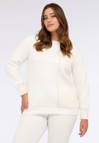 Felpa bianca con un pannello laterale testurizzato, scollo rotondo e maniche lunghe. Realizzata in un materiale morbido con una vestibilità comoda.
