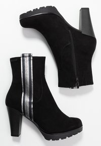 Botines negros de ante con un acento de rayas plateadas, cremallera lateral y un tacón grueso y texturizado, que presentan una suela de goma para mayor agarre.