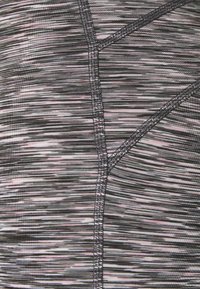 Gros plan d’un tissu rayé rose, noir et blanc avec des coutures grises visibles créant des motifs géométriques de couture.