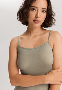 Top senza maniche di un verde chiaro realizzato in un tessuto morbido e liscio. Presenta spalline sottili e un collo arrotondato, con una silhouette aderente.