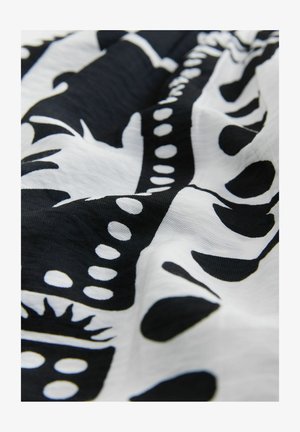 Crno-bijela tkanina s apstraktnim uzorkom oblika, linija i točaka. Materijal izgleda lagano i teksturirano.