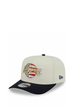 White and black snapback cap featuring a Los Angeles Lakers logo with an American flag design on the front panel.