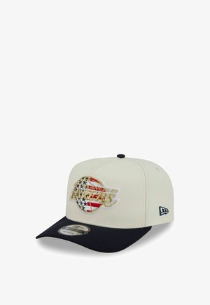 White and black snapback cap featuring a Los Angeles Lakers logo with an American flag design on the front panel.