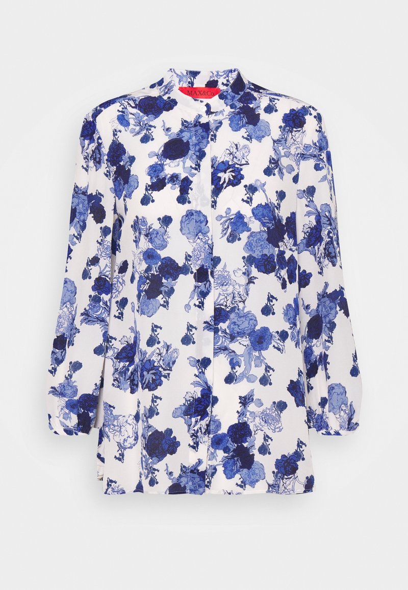 Långärmad blus i vitt med ett blått blommönster, med mandarinkrage och knappstängning fram. Slätt, lätt tyg.