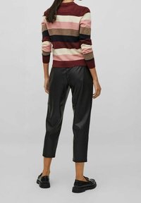 Gestreepte trui in bordeauxrood, roze en crème; gecombineerd met zwarte cropped broek van nep leer; model draagt zwarte schoenen.