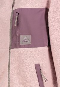 Fleece jacket in soft pink with purple accents. Features a zippered chest pocket, textured fabric, and a triangular logo label.