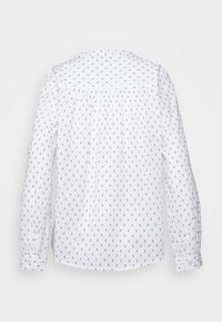 Camicia bianca a maniche lunghe con piccolo motivo a pois blu navy, polsini con bottone, parte posteriore plissettata e colletto arrotondato. Tessuto morbido.