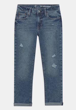 Jean en denim bleu avec légère usure, revers roulés, bouton et fermeture éclair à l'avant, et design à cinq poches.