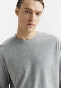 Szary longsleeve z okrągłym dekoltem, wykonany z miękkiego materiału. Charakteryzuje się prostym designem, bez wzorów czy dodatków. Lekko luźny krój.