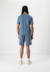 Blauwe katoenen T-shirt en bijpassende shorts met een rode "MALIBU" graphic. Heeft een ronde hals, een relaxte pasvorm en een zachte textuur. Casual kleding.