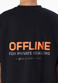 Tricou din bumbac negru, cu text proeminent portocaliu "OFFLINE" și text gri "FOR PRIVATE REASONS" pe spate, design minimalist, croială lejeră.