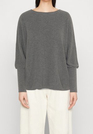 Pull en ribbed gris à manches longues et encolure large, associé à un pantalon ample de couleur claire. Texture douce, design décontracté.