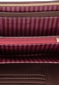 Braunes synthetisches Innenfutter des Geldbeutels mit einer Reißverschlusstasche, ausgestattet mit einem gestreiften Futter in Pink und Kastanienbraun sowie strukturierten braunen Lederakzenten.