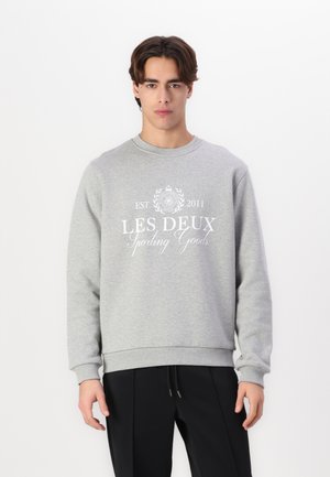 Gray sweatshirt with crew neckline, ribbed cuffs and hem, featuring white printed text "LES DEUX Sporting Goods" and decorative logo.