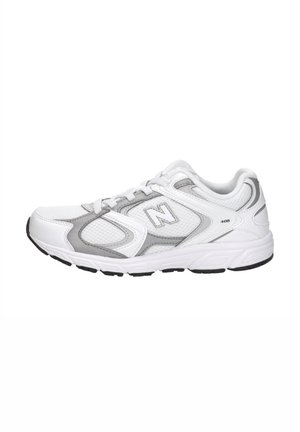 Scarpa sportiva New Balance bianca e grigia con pannelli in mesh, chiusura con lacci e suola in gomma nera, vista laterale.