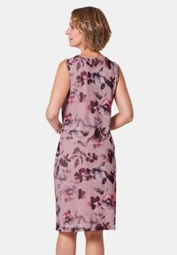 Robe florale avec une coupe ajustée, sans manches, en tissu rose pâle avec des motifs abstraits violets foncés et bordeaux.