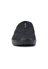 Schwarzer Slipper mit einer gesteppten, strukturierten Oberseite, Gummisohle und einem Tag mit der Aufschrift "oofos" an der Rückseite. Entwickelt für Komfort und einfache Handhabung.