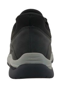 Melnas sporta kurpes ar gludu augšējo daļu, izliekta forma, mīksts apkakle un pelēks apakšējais slānis ar teksturētām rakstu līnijām, kas nodrošina saķeri.