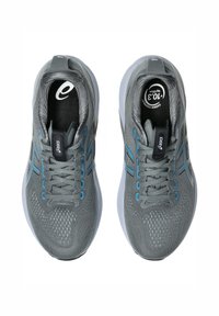 Grå träningsskor med överdel i mesh, blå accenter, rund tå och vadderad krage. Utrustade med snören och en dämpad sula för komfort.