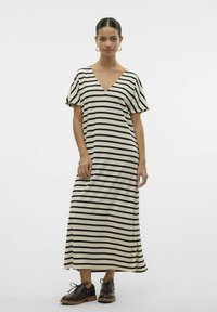 Robe maxi rayée en crème et noir, avec un décolleté en V, des manches courtes et une coupe décontractée. Portée avec des chaussures à lacets marron.