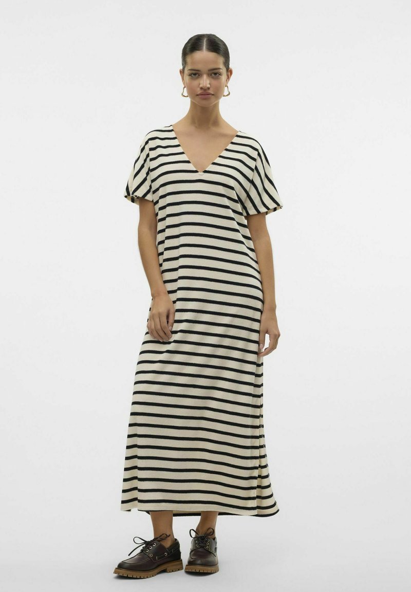 Robe maxi rayée en crème et noir, avec un décolleté en V, des manches courtes et une coupe décontractée. Portée avec des chaussures à lacets marron.