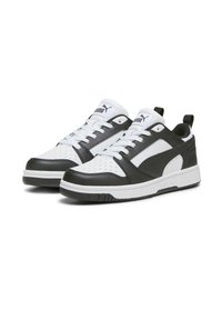 Svarta och vita sneakers med en slät läderöverdel, perforerad tåbox, tjock vit sula och en dragtab vid hälen.