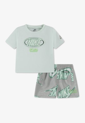 Maglietta Nike verde chiaro a maniche corte con grande logo e pantaloncini verde-grigio coperti da grandi loghi Nike.