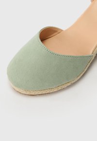 Lys grønn semsket espadrille med rund tå og åpen overdel, med såle av naturlig jute. Glatt innersåle.